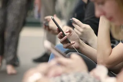 An illustration depicting a person immersed in their phone, surrounded by TikTok icons and videos, symbolizing the all-encompassing nature of TikTok addiction and its hold on users' attention.